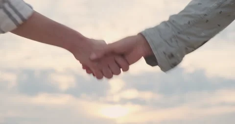 Handshake against backdrop of setting sun and sky. Man and woman greet each 動画素材 247913404