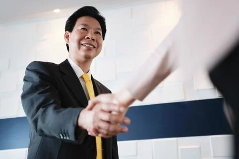 Handshake Between Happy Asian Manager And Hispanic Businesswoman In Office Stock Photos