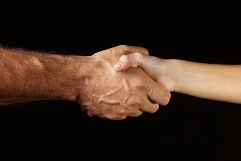 Handshake Between Two Hands Against a Dark Background 스톡 사진