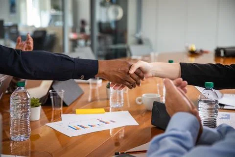 Handshake between two people of different ethnicities during a meeting in a.. Stock Photos
