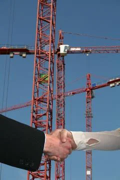 Handshake with construction cranes Stock Photos