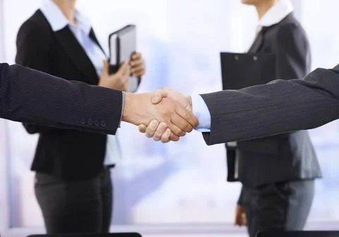 Handshake in focus Closeup handshake in focus, businesswomen in background... Stock Photos
