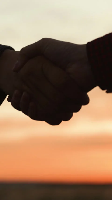 Handshake at sunset, silhouette in park field. At dawn in agricultural field Stock Footage 293666078