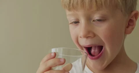Handsome 5 year old boy drinks orange juice and licks lips. Clouse up Vídeo Stock 283047310