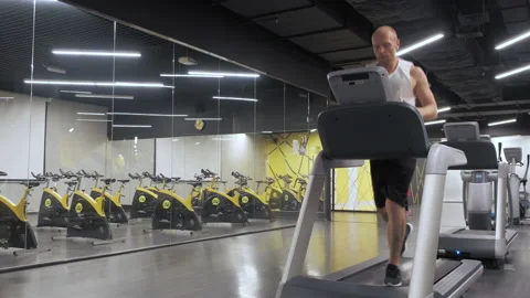 Handsome active man running on treadmill in modern gym Stock Footage 141988248