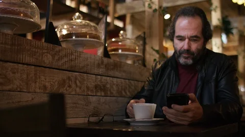 Handsome affluent older male drinking coffee as he checks his cell phone Stock Footage 102436038