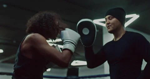 Handsome african guy is training in boxing club, practicing punches with coach Stock Footage 203812608