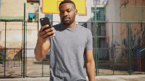 Handsome African guy walking through the street, holding skateboard in hand Video stock 92055620