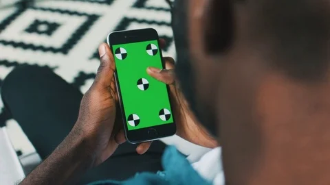 Handsome african man sitting on sofa using smart phone with track motion. Young Stock Footage 75728734