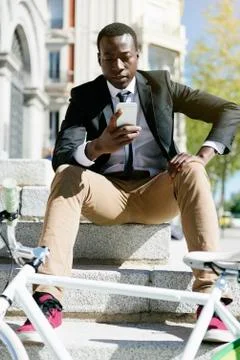 Handsome african man smiling when he is using his mobile. Stock Photos