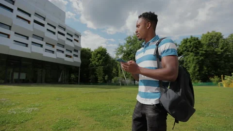 Handsome afro-american man using smartphone on the background of the university Stock Footage 155678716