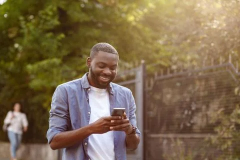 Handsome Afro-American man using smartphone and smiling. Happy man using mobile Stock Photos