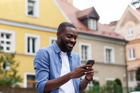 Handsome Afro-American man using smartphone and smiling. Happy man using mobile Stock Photos