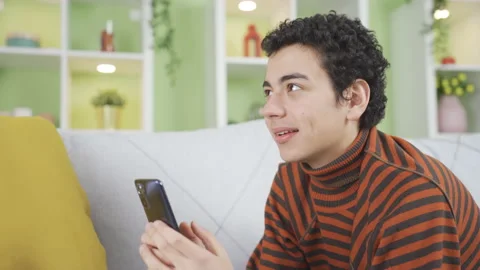 Handsome and attractive boy using phone at home, texting, dating. Stock-Footage 233556694