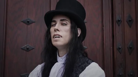 Handsome and mysterious gothic vampire with long hair showing his fangs Stock Footage 284843977