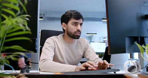 Handsome Arab man sitting at computer screen and typing on keyboard. Customer Stock Footage 179987740