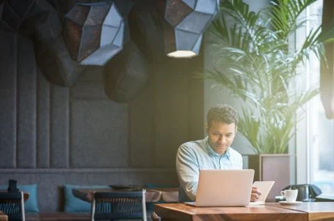Handsome Arabian guy is making notes from computer Stock Photos