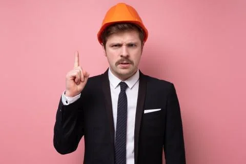 Handsome architect in protective helmet looking at camera seriously. Stock Photos