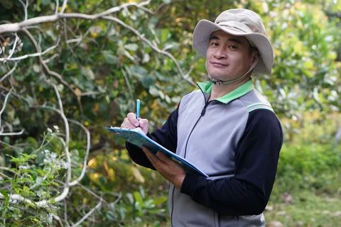 Handsome Asian man botanist is at forest to survey botanical plants Stock Photos