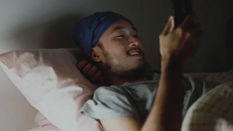 Handsome Asian man using a mobile phone while Lying on Bed at home. Stock Footage 116648196