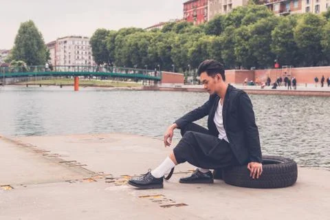 Handsome Asian model posing by an artificial basin Stock Photos
