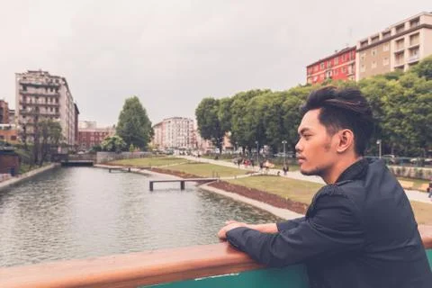 Handsome Asian model posing by an artificial basin Stock Photos