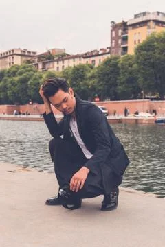 Handsome Asian model posing by an artificial basin Stock Photos