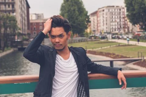 Handsome Asian model posing by an artificial basin Stock Photos