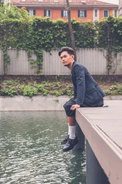 Handsome Asian model posing by an artificial basin Stock Photos