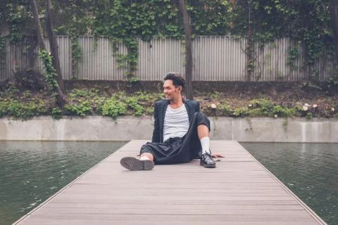 Handsome Asian model posing by an artificial basin Stock Photos