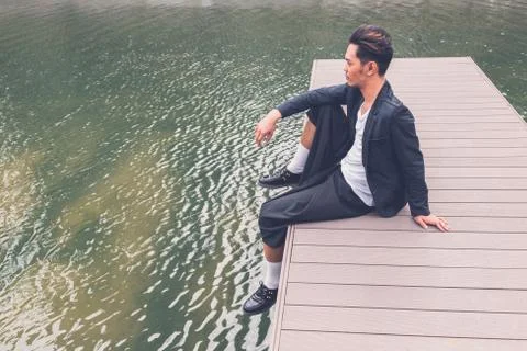 Handsome Asian model posing by an artificial basin Stock Photos