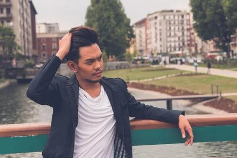 Handsome Asian model posing by an artificial basin Stock Photos