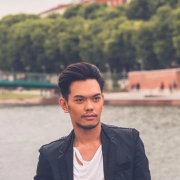 Handsome Asian model posing by an artificial basin Stock Photos