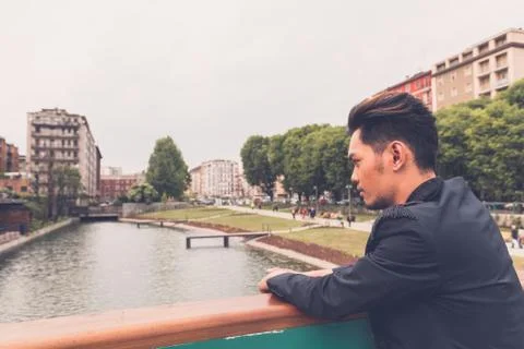 Handsome Asian model posing by an artificial basin Stock Photos