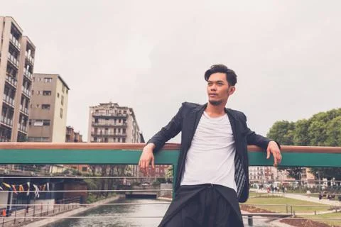 Handsome Asian model posing by an artificial basin Stock Photos