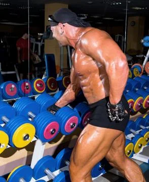 Handsome athletic man bodybuilder doing exercises with dumbbell in gym 写真素材
