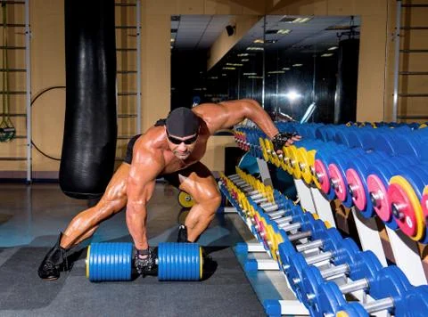 Handsome athletic man bodybuilder doing exercises with dumbbell in gym 库存照片
