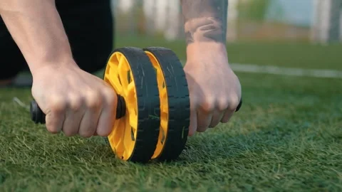 Handsome athletic man doing abs exercises using abdominal roller at stadium Video stock 260829503