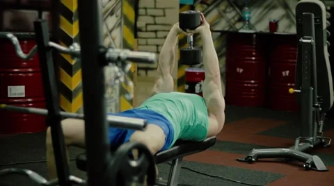 Handsome athletic man doing pectorals with pull over exercize with dumbbell on t Video stock 63216439