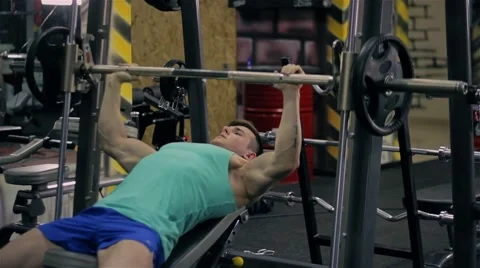 Handsome athletic man doing pectorals with bench press trainer with dumbbells on Stock Footage 63217760