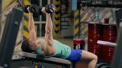 Handsome athletic man doing pectorals with bench press with dumbbells on bench i Video stock 63220472