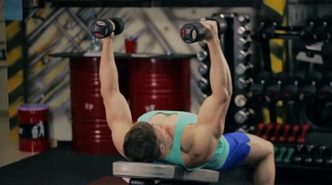 Handsome athletic man doing pectorals with breeding hands with dumbbells on benc 库存影片 63220596