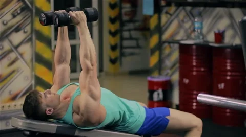 Handsome athletic man doing pectorals with breeding hands with dumbbells on benc Stock Footage 63220597