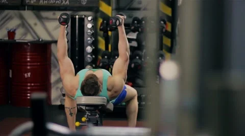 Handsome athletic man doing pectorals with breeding hands with dumbbells on benc Video stock 63220613