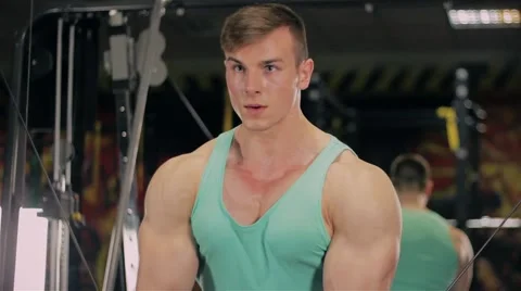 Handsome athletic man doing pectorals on the crossover trainer in the GYM close  Video stock 63220615