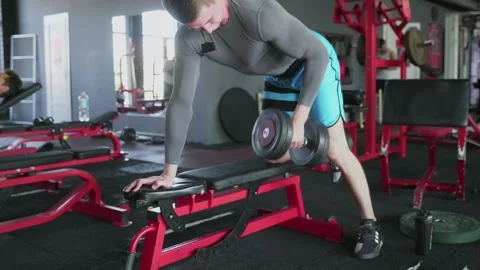 Handsome athletic man performing One-arm dumbbell row at gym Stock Footage 143522187