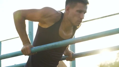 Handsome athletic man training on parallel crossbars, physical strength, health Stock Footage 83072488