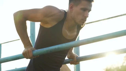 Handsome athletic man training on parallel crossbars, physical strength, health Stock Footage 83076806