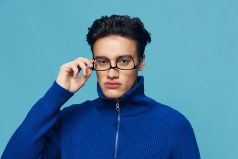A handsome, attractive man stands on a light blue background in a blue zip-up Stock Photos