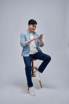 Handsome attractive man using a mobile phone and sitting on a chair isolate.. Stock Photos